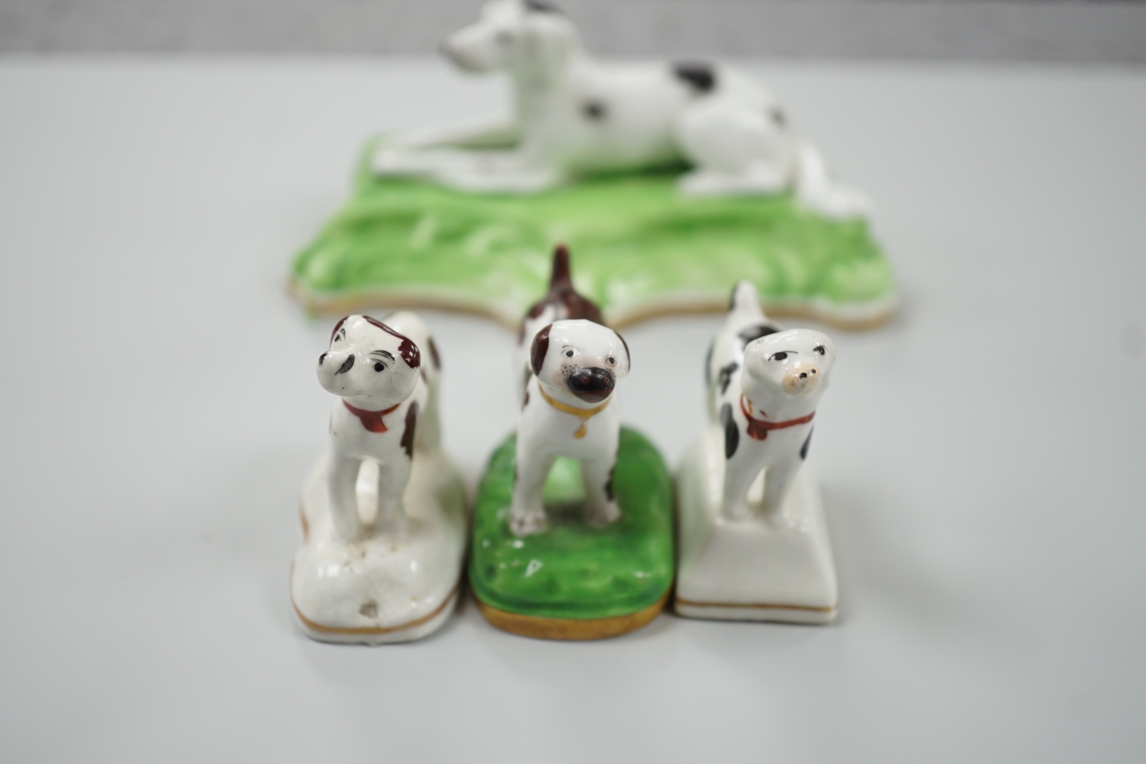 Three toy Staffordshire models of standing terriers; two with brown spots and the other black spots, together with a small Staffordshire model of a recumbent black and white setter on modelled base. c.1830-50, Largest 13